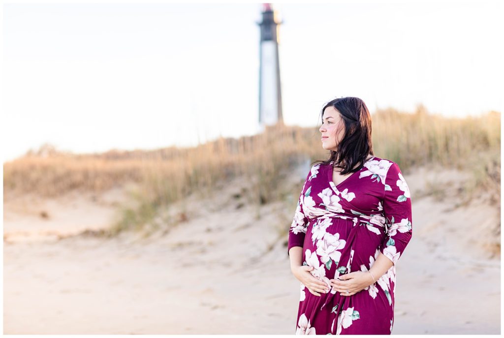 mother on the beach during the fall holding baby belly during maternity photo session